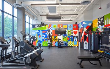 a gym with cardio machines and a colorful wall with a television at Inspire West Town, CHICAGO, 60642
